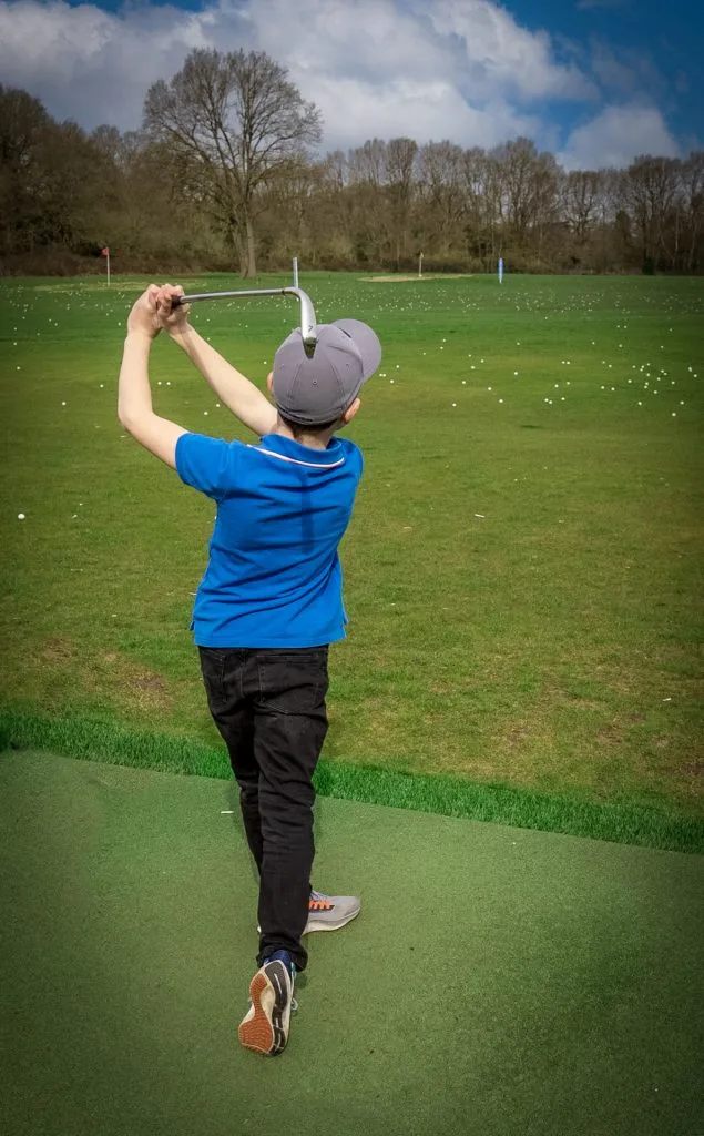 Young boy hitting golf balls at the TrackMan driving range in Telford at The Shropshire Golf Club, part of junior golf lessons and beginner golf in Telford