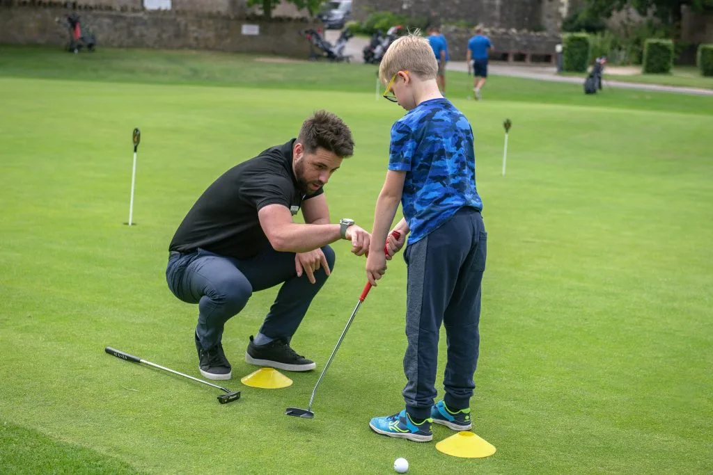 Young boy receiving a putting golf lesson in Telford at The Shropshire Golf Club, part of junior golf coaching and beginner golf in Telford